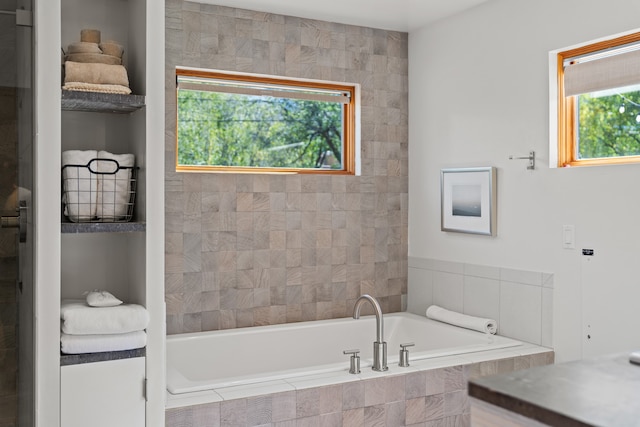 bathroom featuring a wealth of natural light and tiled bath