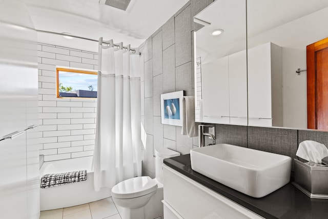 full bathroom featuring tile patterned flooring, toilet, shower / bath combo with shower curtain, vanity, and tile walls