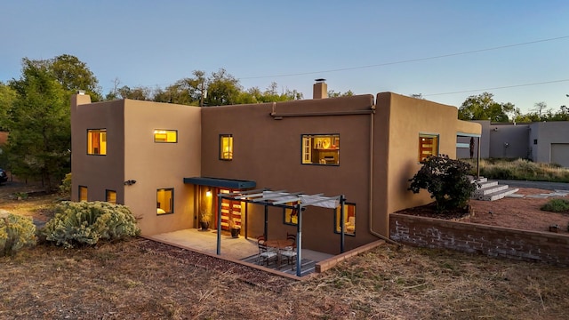 rear view of house featuring a patio, a chimney, and stucco siding