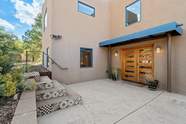 property entrance featuring a garage, stucco siding, and french doors