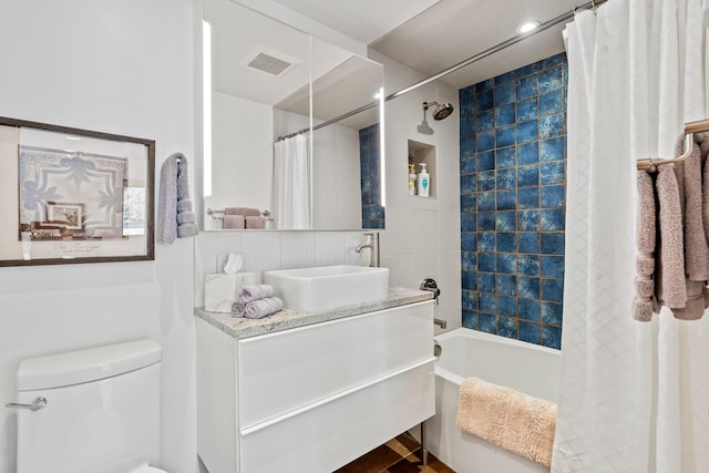 full bathroom featuring visible vents, vanity, shower / bath combo with shower curtain, and toilet