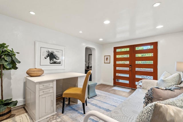 foyer featuring arched walkways, light wood-style flooring, baseboards, and recessed lighting