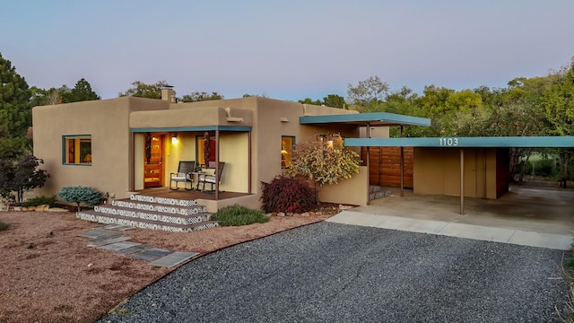 back of property featuring driveway, a carport, and stucco siding