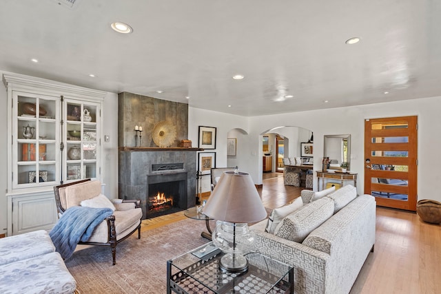 living room featuring a tile fireplace and light wood-type flooring