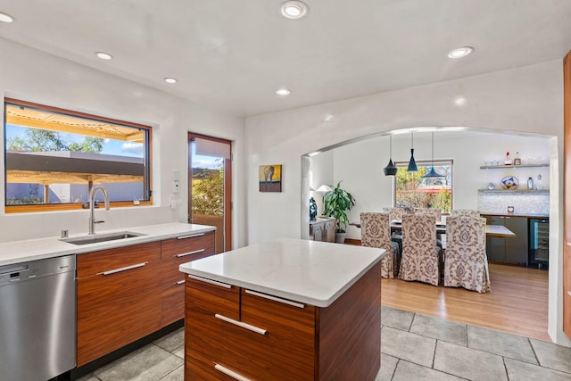 kitchen with dishwasher, a kitchen island, light countertops, pendant lighting, and a sink