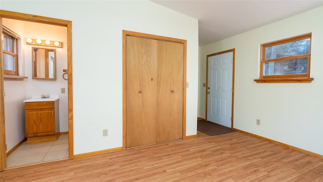 unfurnished bedroom with light hardwood / wood-style flooring, ensuite bath, and a closet