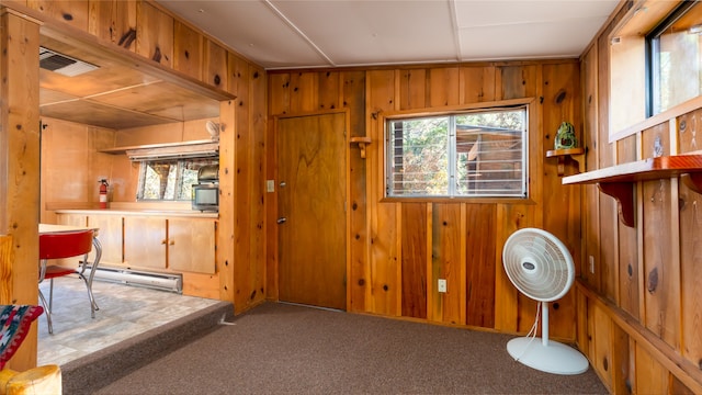 interior space featuring baseboard heating, wood walls, and carpet floors