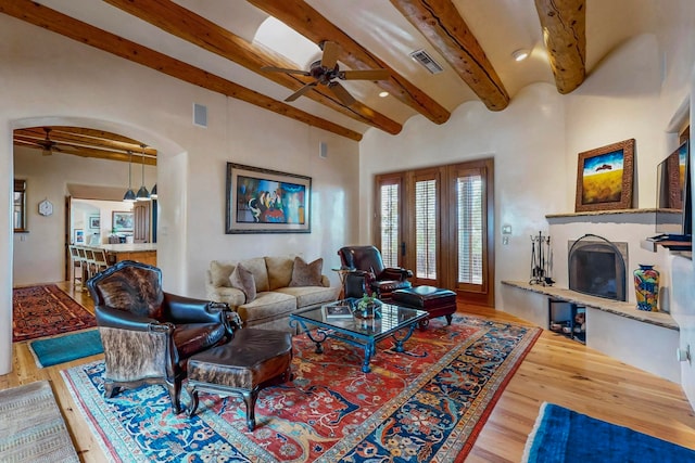 living room with hardwood / wood-style flooring, ceiling fan, and beamed ceiling