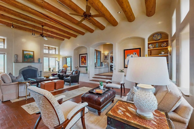 living room with beamed ceiling, a high ceiling, and ceiling fan