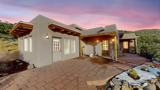 back house at dusk featuring a patio