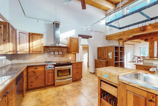 kitchen with wall chimney range hood, decorative backsplash, light tile patterned floors, appliances with stainless steel finishes, and beamed ceiling