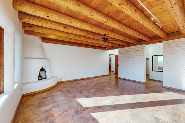 unfurnished living room featuring beam ceiling, ceiling fan, a large fireplace, track lighting, and wood ceiling