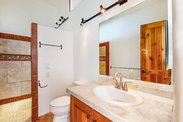 bathroom featuring tiled shower, vanity, and toilet