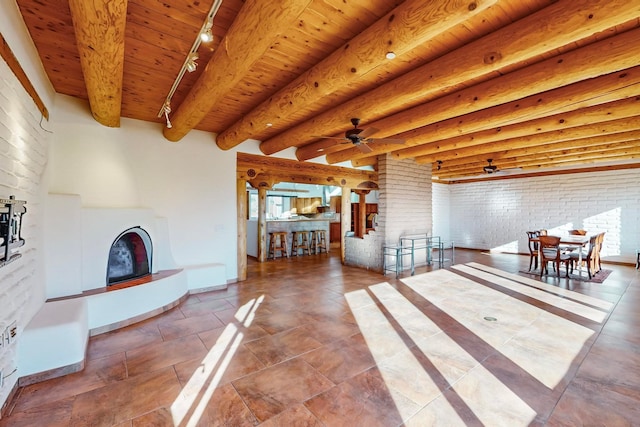 living room featuring track lighting, wood ceiling, brick wall, ceiling fan, and beam ceiling