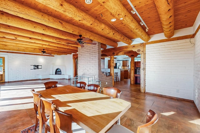 dining space featuring wood ceiling, ceiling fan, a fireplace, and brick wall