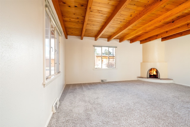 spare room featuring a fireplace, carpet floors, beamed ceiling, and wood ceiling