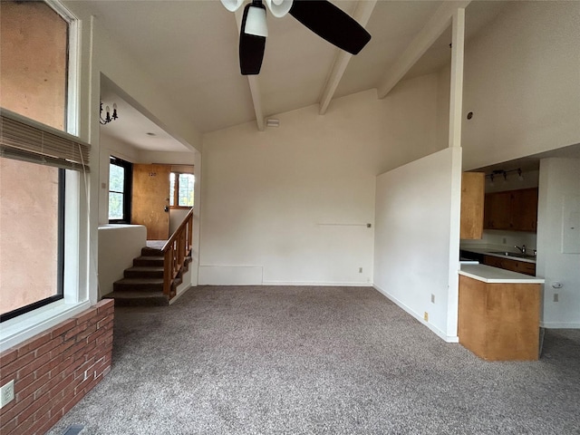 unfurnished living room with carpet, a towering ceiling, sink, ceiling fan, and beamed ceiling