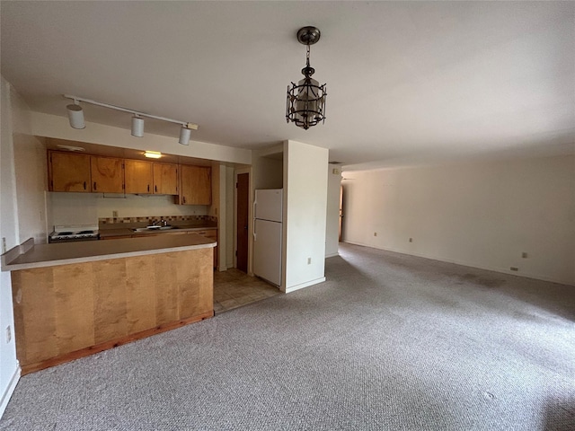 kitchen featuring track lighting, decorative light fixtures, white refrigerator, sink, and light colored carpet