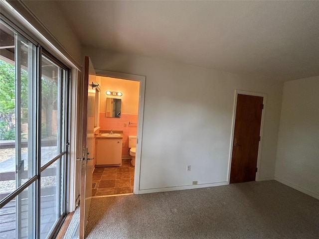 unfurnished bedroom featuring sink, tile walls, connected bathroom, access to exterior, and light colored carpet