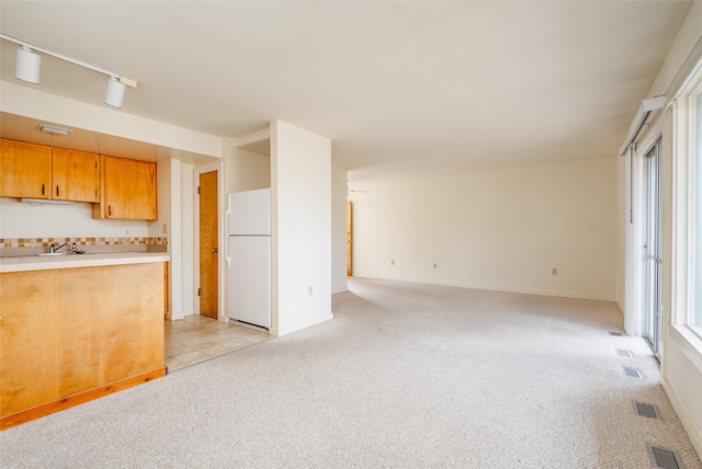 kitchen featuring white fridge, light colored carpet, and a healthy amount of sunlight