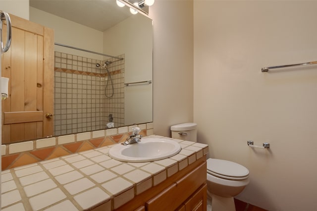 bathroom featuring a tile shower, vanity, and toilet