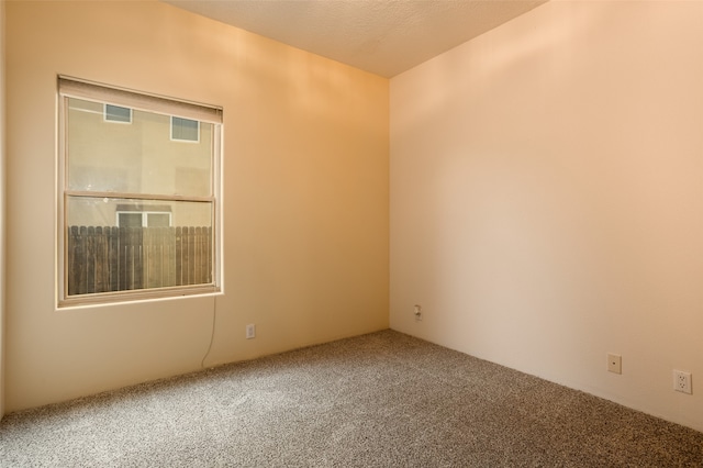 carpeted empty room featuring a textured ceiling