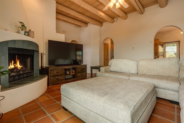 tiled living room with beam ceiling, a tile fireplace, ceiling fan, wooden ceiling, and a high ceiling