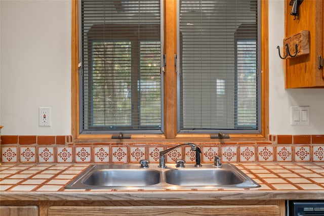 interior details with tile countertops, decorative backsplash, and sink