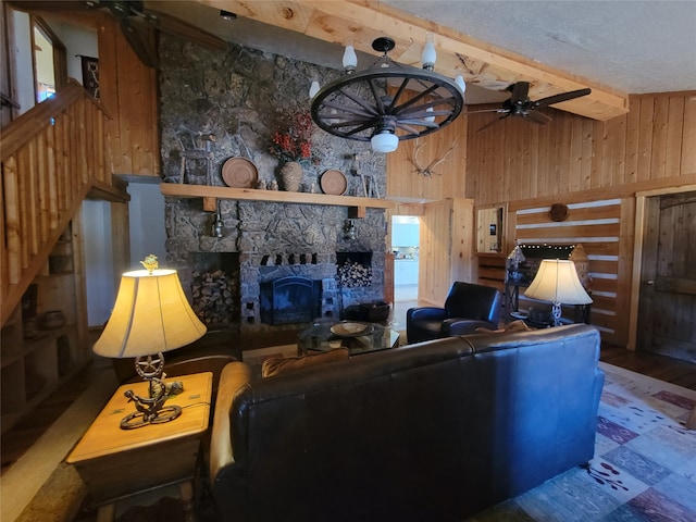 living room with a stone fireplace, wooden walls, ceiling fan, a textured ceiling, and wood-type flooring