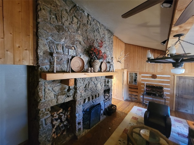 living room with wood walls, a stone fireplace, and light hardwood / wood-style floors