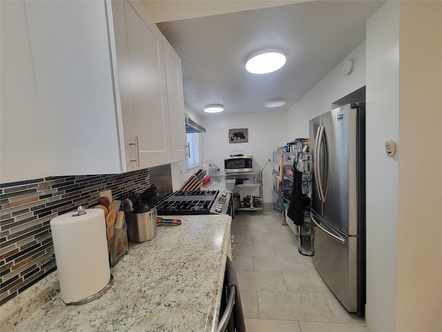 kitchen with light stone countertops, stainless steel appliances, white cabinetry, and tasteful backsplash