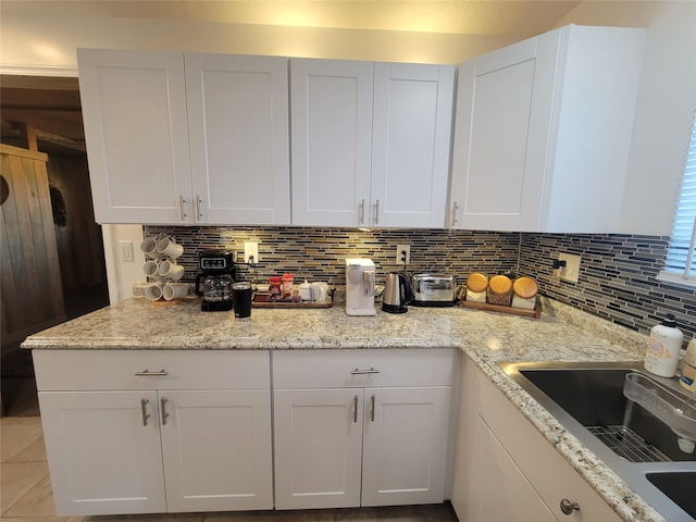 kitchen with white cabinets, backsplash, and light stone countertops