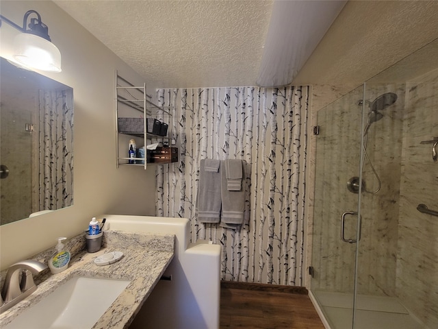 bathroom featuring vanity, wood-type flooring, a textured ceiling, and walk in shower