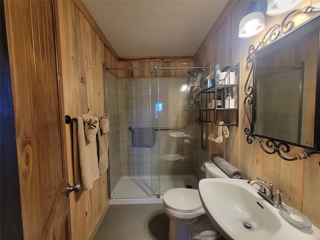 bathroom featuring wood walls, toilet, a shower with door, and sink