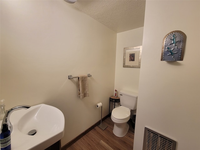 bathroom featuring hardwood / wood-style floors, toilet, sink, and a textured ceiling