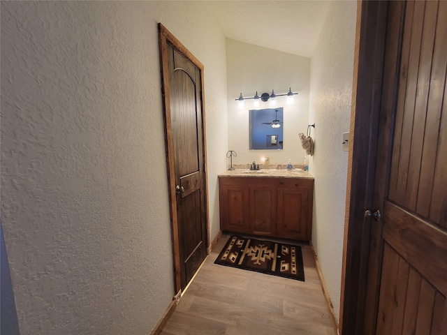 bathroom featuring hardwood / wood-style floors, vanity, and vaulted ceiling