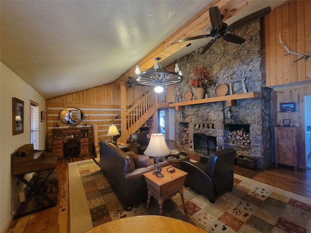 living room with a stone fireplace, wood walls, wood-type flooring, and lofted ceiling