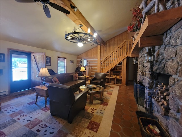 living room featuring ceiling fan with notable chandelier, lofted ceiling with beams, a stone fireplace, and wooden walls