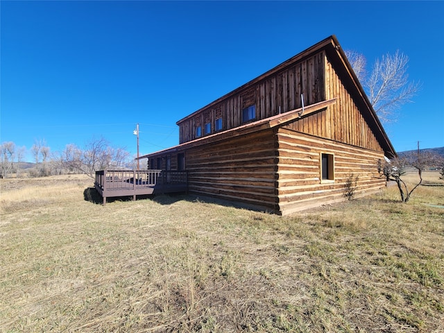 view of side of home with a wooden deck and a yard