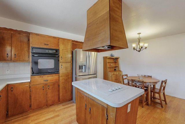 kitchen with oven, stainless steel fridge, white electric cooktop, light wood-type flooring, and decorative light fixtures