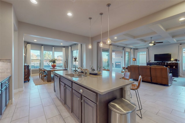 kitchen with decorative light fixtures, sink, a wealth of natural light, and an island with sink