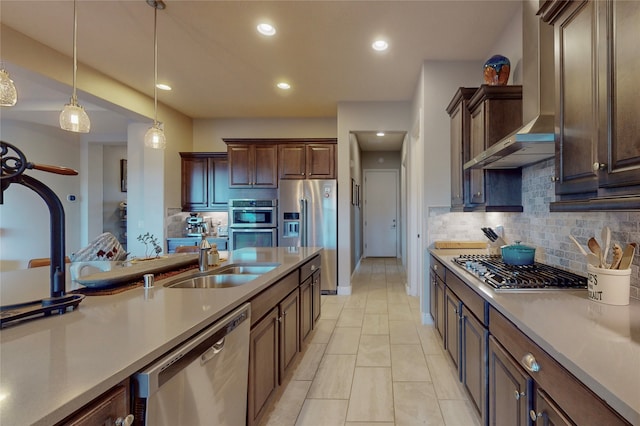 kitchen with sink, wall chimney range hood, pendant lighting, decorative backsplash, and appliances with stainless steel finishes