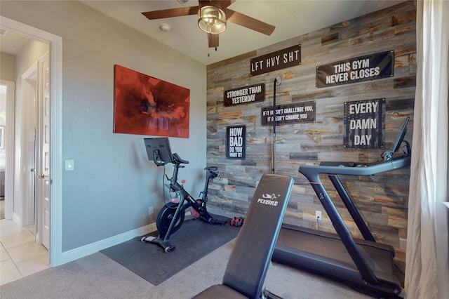 workout area with light tile patterned floors, ceiling fan, and wooden walls