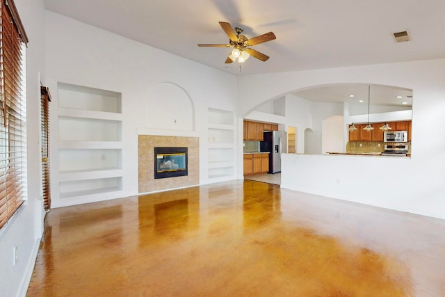 unfurnished living room with ceiling fan, built in features, and a fireplace