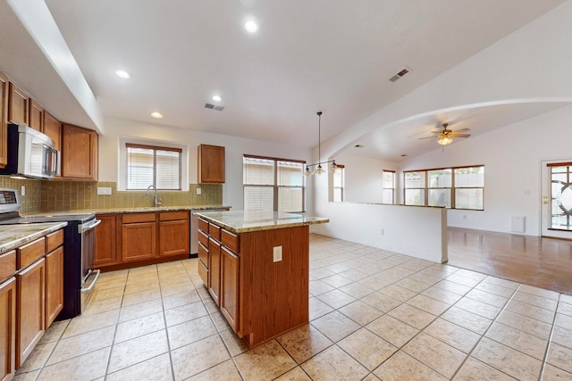 kitchen with ceiling fan, a center island, stainless steel appliances, pendant lighting, and vaulted ceiling