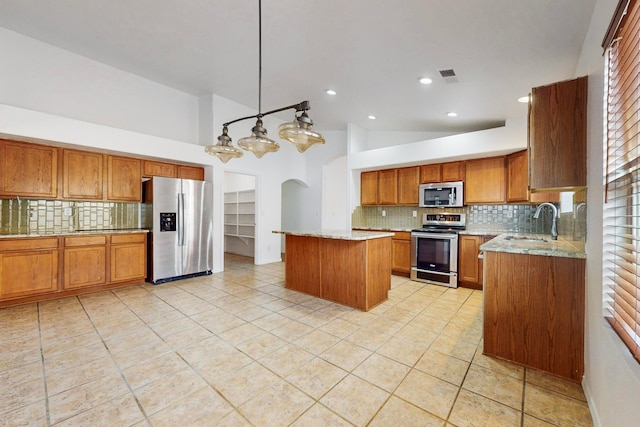 kitchen with appliances with stainless steel finishes, backsplash, sink, decorative light fixtures, and a kitchen island