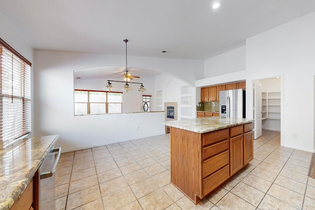 kitchen with ceiling fan, a kitchen island, stainless steel refrigerator with ice dispenser, and a wealth of natural light