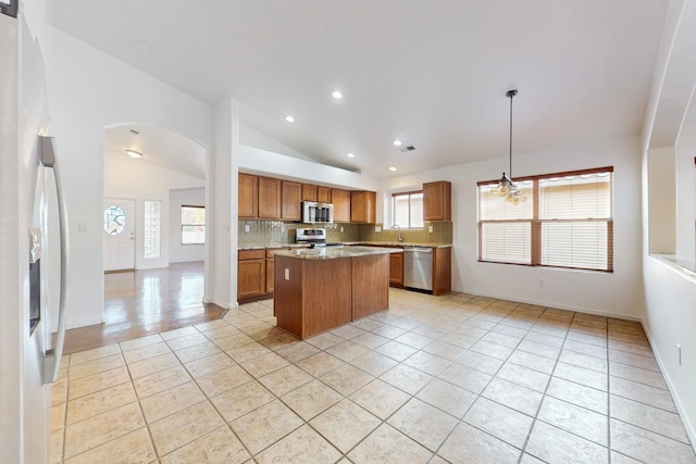 kitchen with stainless steel appliances, vaulted ceiling, hanging light fixtures, and a healthy amount of sunlight