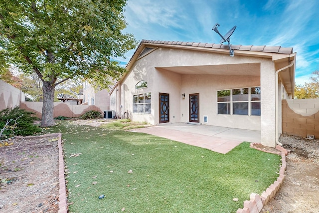 back of property with a patio area, a yard, and central AC