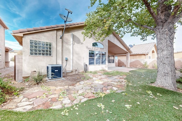 rear view of house with a yard, a patio, and central AC